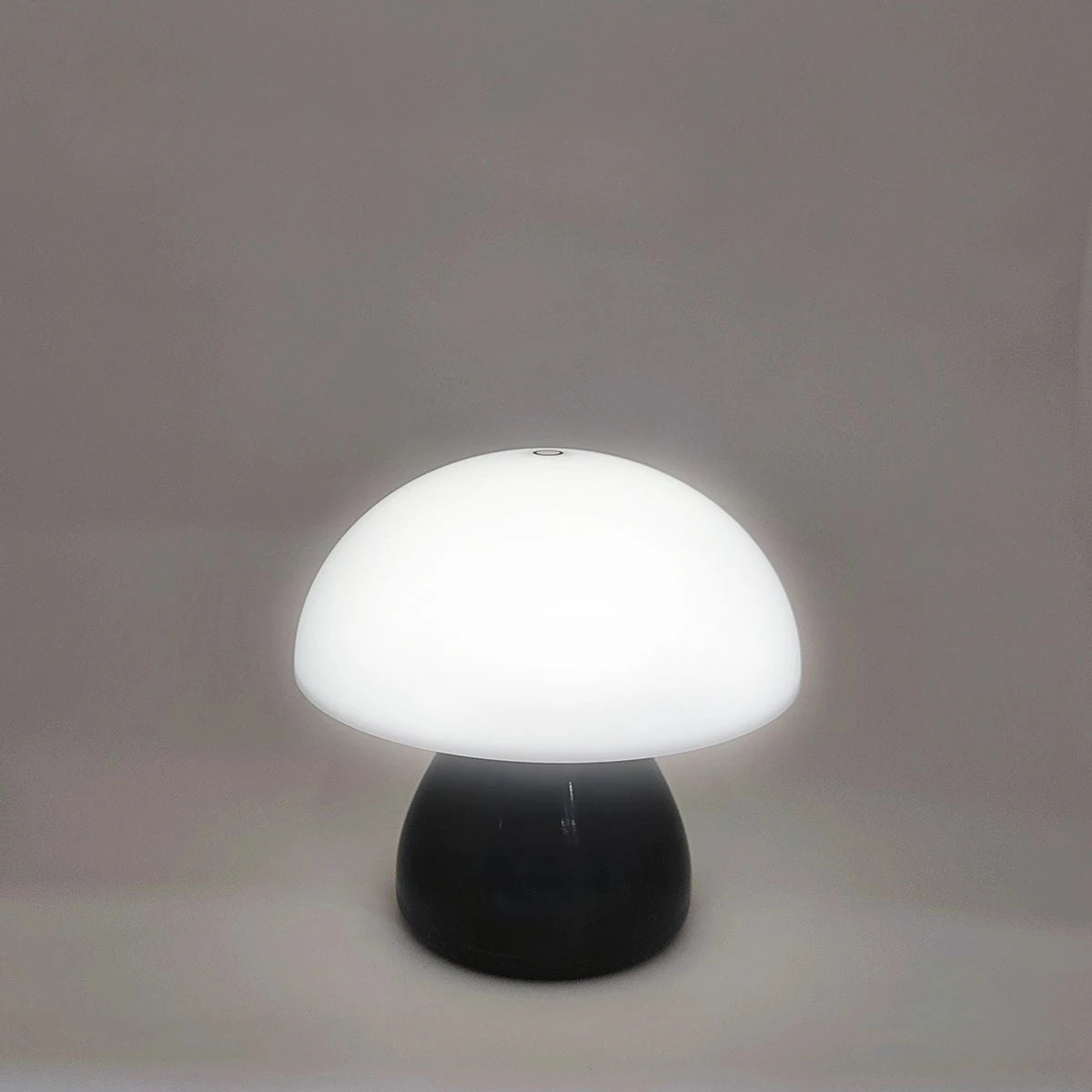 Mushroom-shaped lamp with white shade and black base on a plain background
